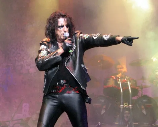 Quelle est la signification du geste caractéristique d'Alice Cooper avec son doigt déganté ?